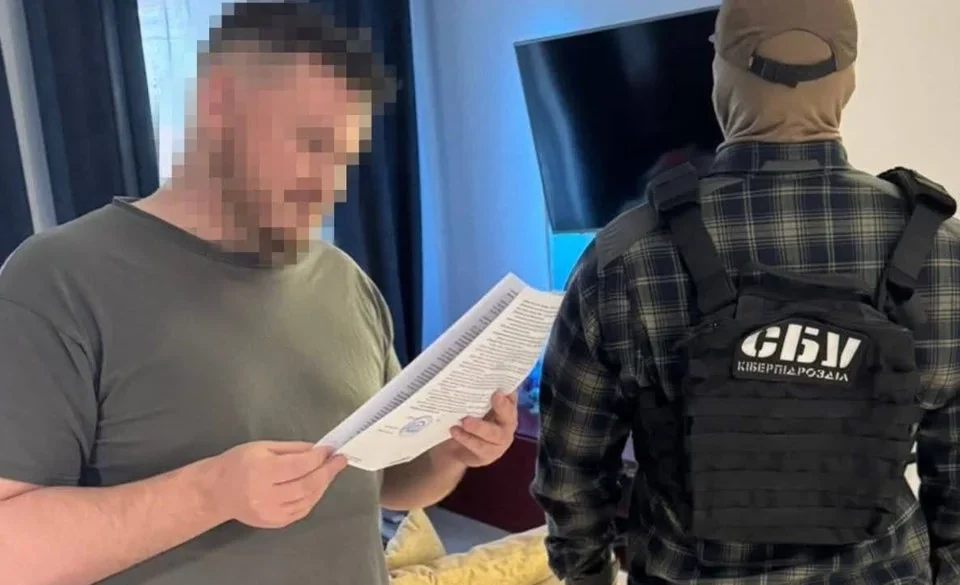 Чоловік з розмитим обличчям читає папери поруч зі співробітником СБУ